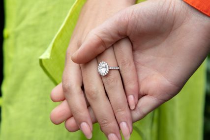 Woman's hand bearing engagement ring, held by man