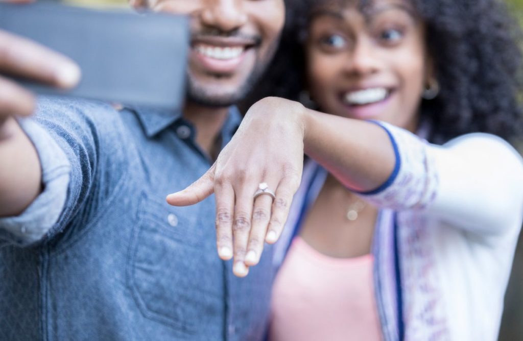 couple posing for selfie and showing off engagement ring
