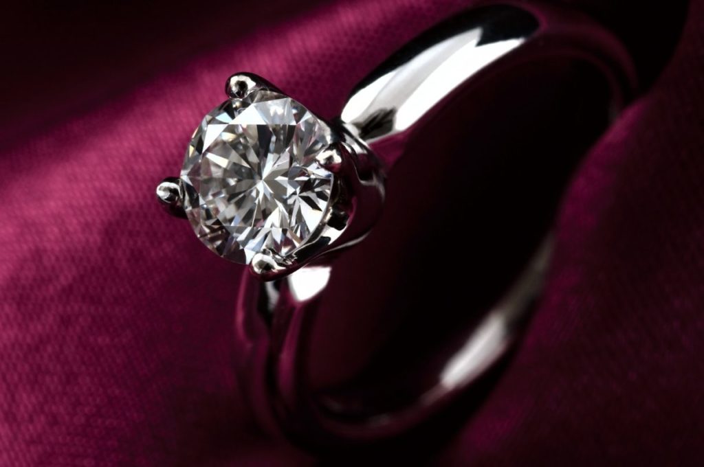 Silver engagement ring sitting on velvet cushion
