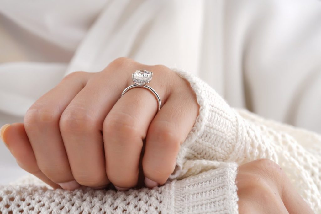 Woman resting her hand on her other hand, and displaying engagement ring.