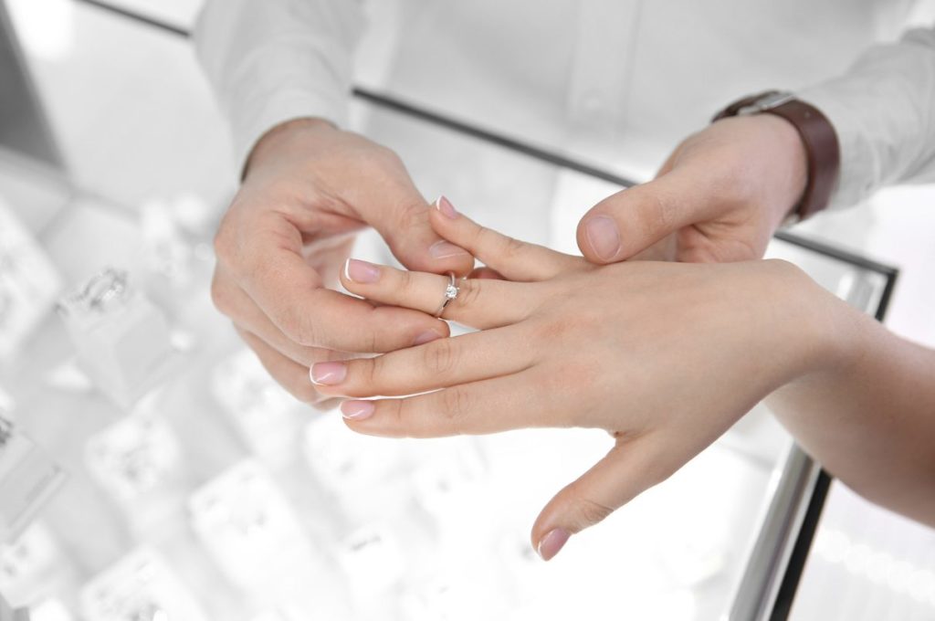 woman's hand trying on an engagement ring over shop counter