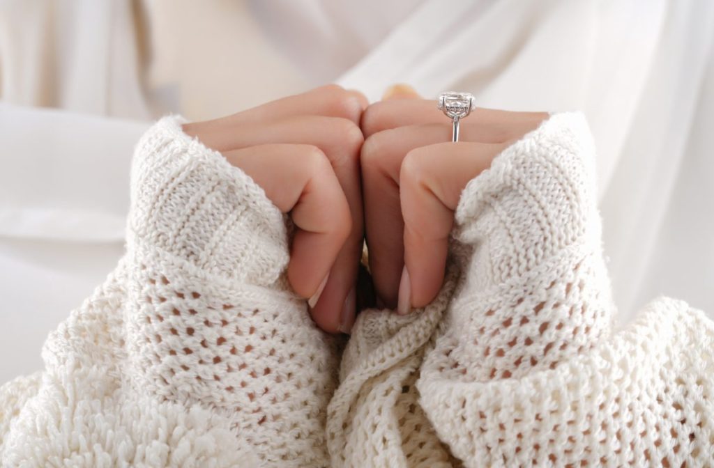 Woman's holding hands together and showing engagement ring.