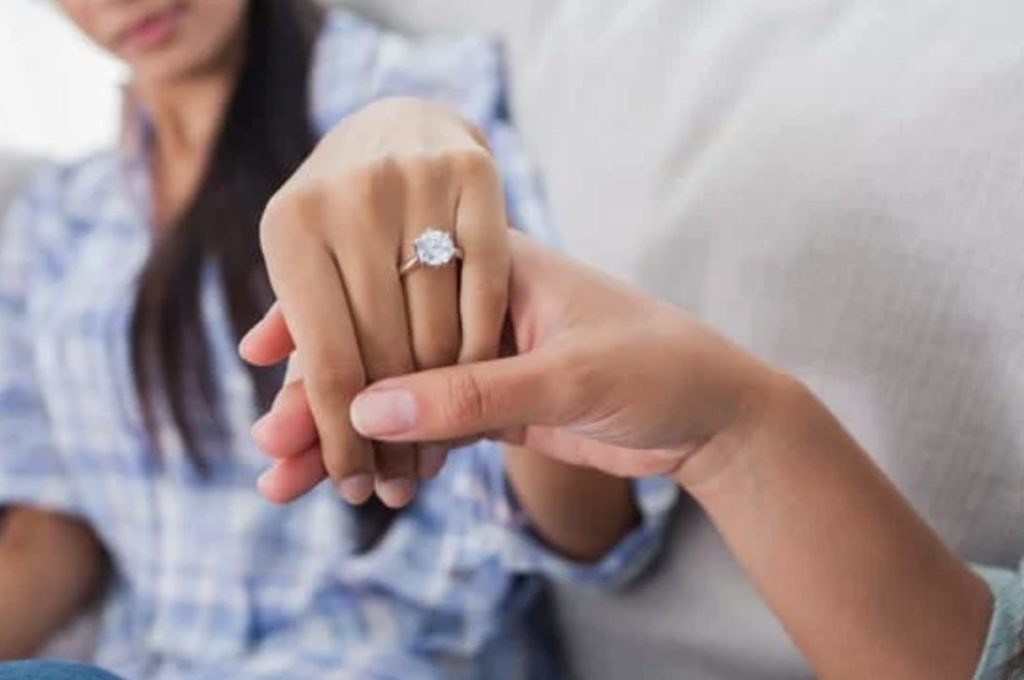 Woman showing off engagement ring with her hand being held by the viewer.