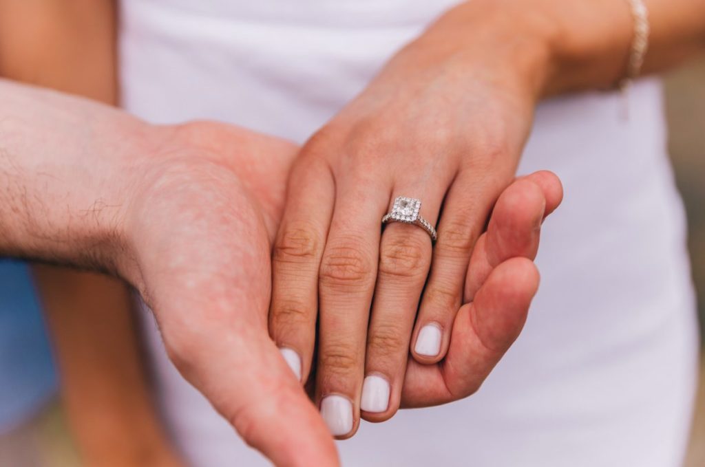 Woman's hand bearing engagement ring, being held by male partner