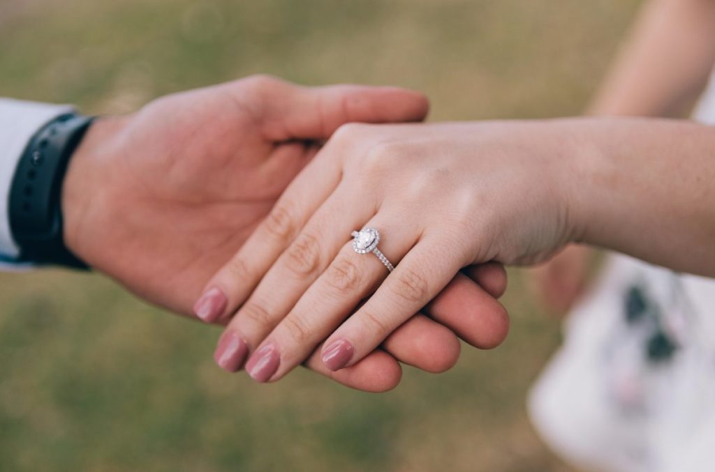 Woman's hand wearing engagement ring being held by man