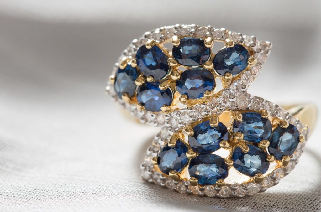 Gold diamond rings with multiple blue encrusted gemstones.