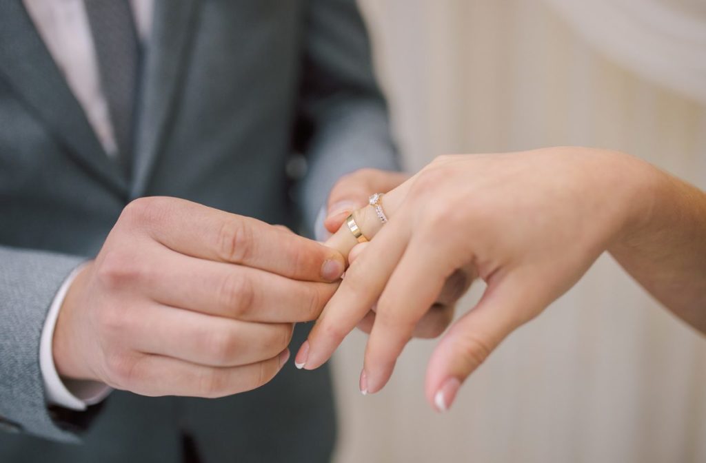 Groom placing wedding ring on bride's finger