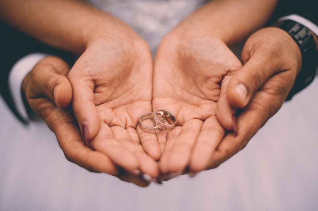 Wedding rings displayed in cupped hands of couple