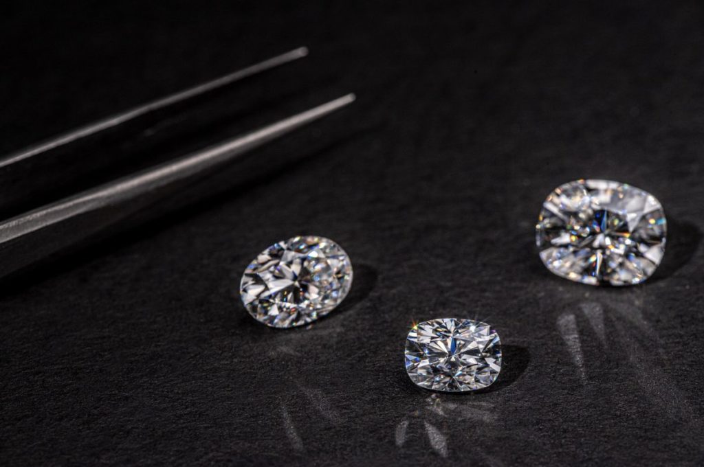 Three round cut diamonds and a set of tweezers.