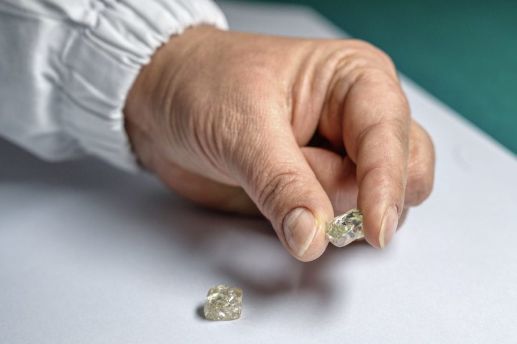 man's hand holding a rough natural diamond